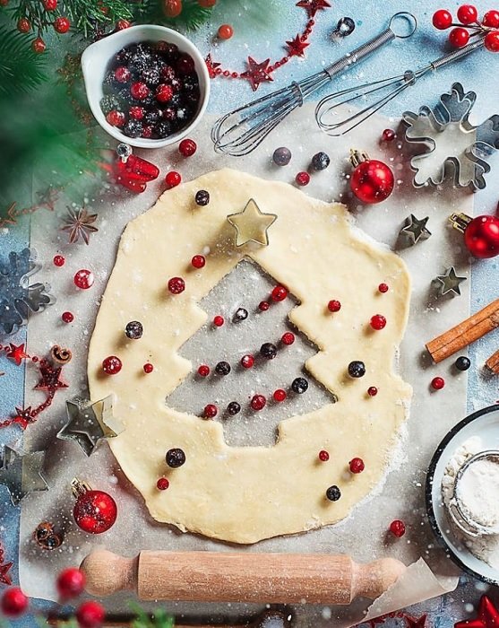 Christmas flat lay of pie dough cut out as a tree baking ingredients and utensils