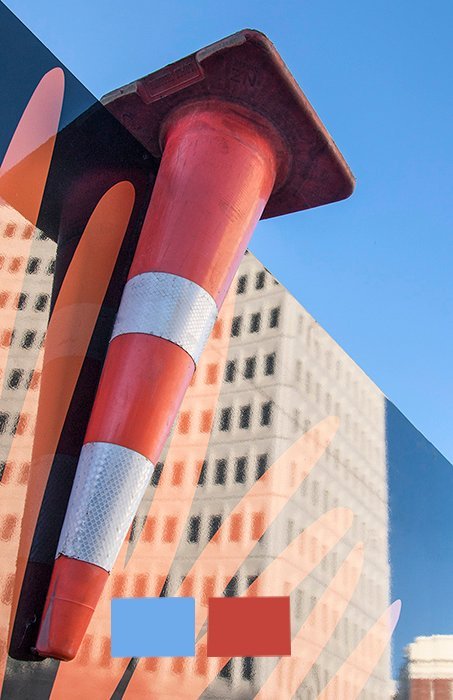 an upside-down traffic cone and building showing orange and blue complementary colors in photography