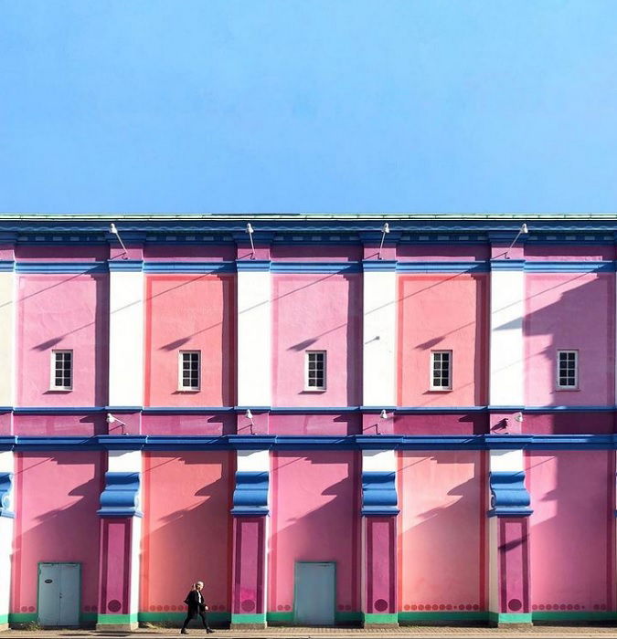 a building painted in pinks and blues is complemented by the cool blue sky above it showing color in photography