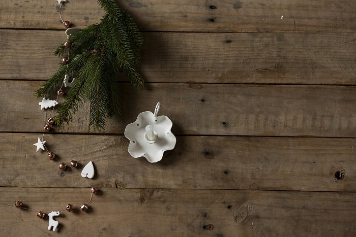 flat lay background idea: unlit candle and pine needles against a wooden background