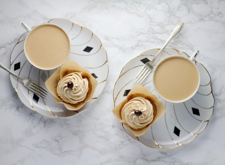 flat lay background idea: tea and a cupcake on a saucer in front of a marble background