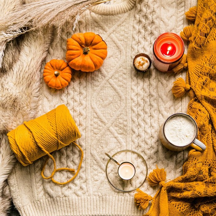 flat lay background idea: pumpkin, hot chocolate, and a candle on top of an autumn sweater