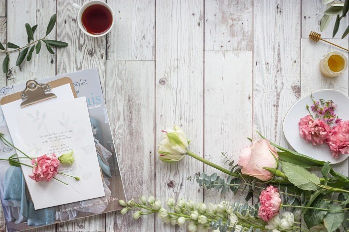flat lay background idea: flowers and an invitation against a faux wood backdrop