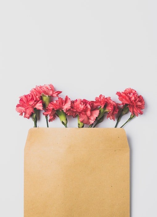 平铺摄影：一个装满鲜花的信封，在开口上方用相机偷看