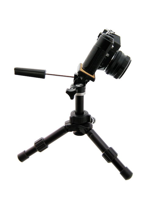 A DSLR camera tilted forward on a tripod for flat lay product photography