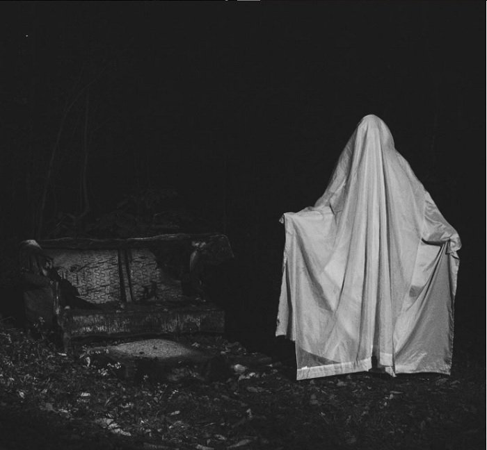 horror photography idea: a person with a white sheet draped over them in a dark and creepy setting