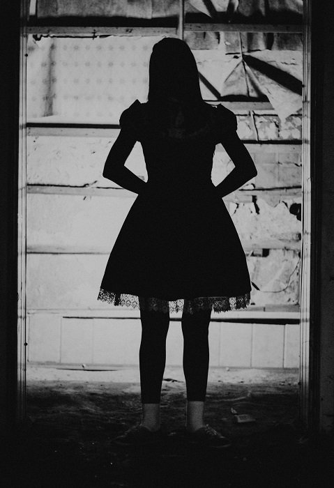 horror photography example: a silhouette of a girl in a dress against a decrepit white background