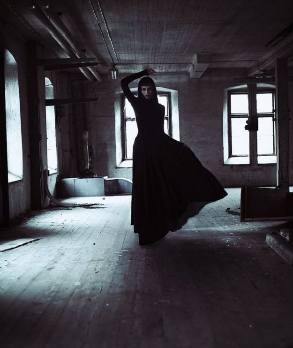 scary horror photography: a possessed woman in a black gown standing in an abandoned haunted building