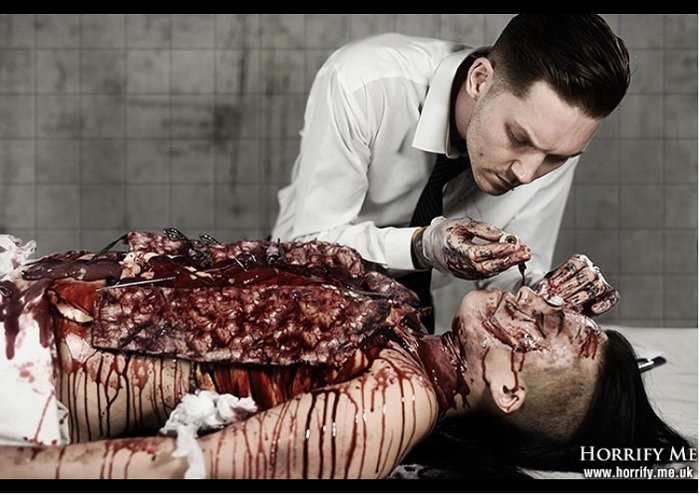 creepy horror photography: a doctor operates with blood soaked hands on a gory patient with their torso cut open