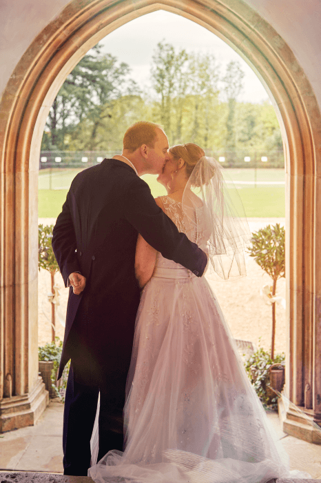 a wedding photo of a couple kissing in the doorway of the chapel