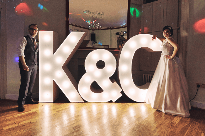 wedding shot idea: Couple stand by giant light up initials at their reception