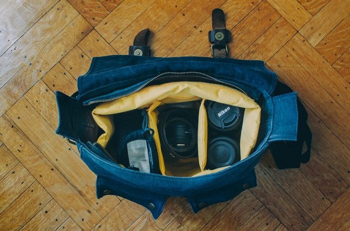 a full messenger camera bag sitting on a hardwood floor