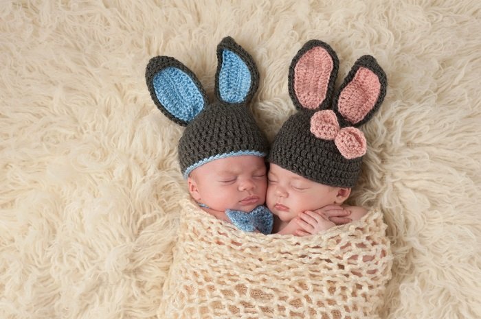 newborn twins photo idea: newborn twins wearing knitted bunny ear hats gentle swaddled together