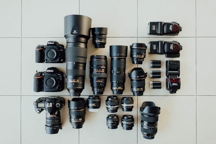 range of Nikon Cameras, lenses, and flashes arranged on a tile floor