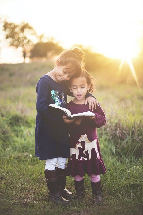 photo ideas for siblings: sisters embracing while reading a book