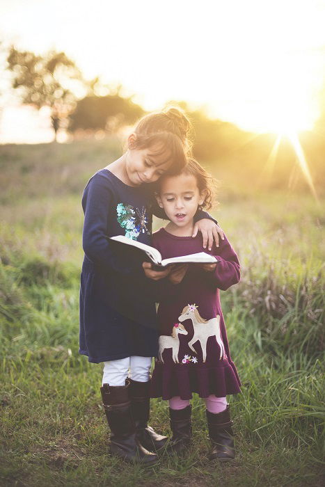 photo ideas for siblings: sisters embracing while reading a book