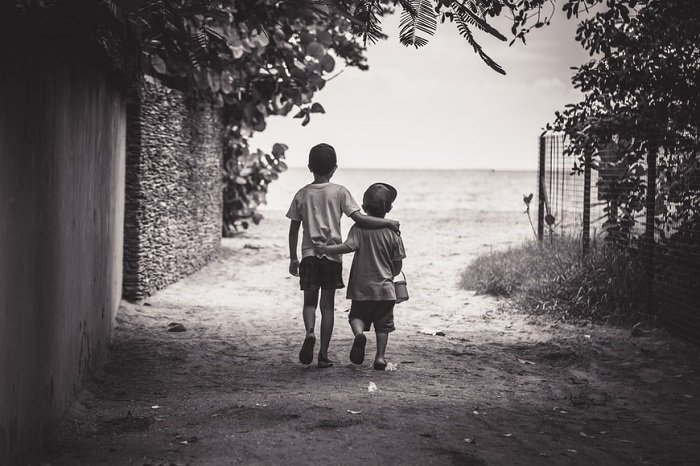photo ideas for siblings: black and white photo of brothers walking away from the camera