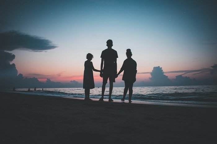 photo ideas for siblings: silhouette of siblings standing by the beach