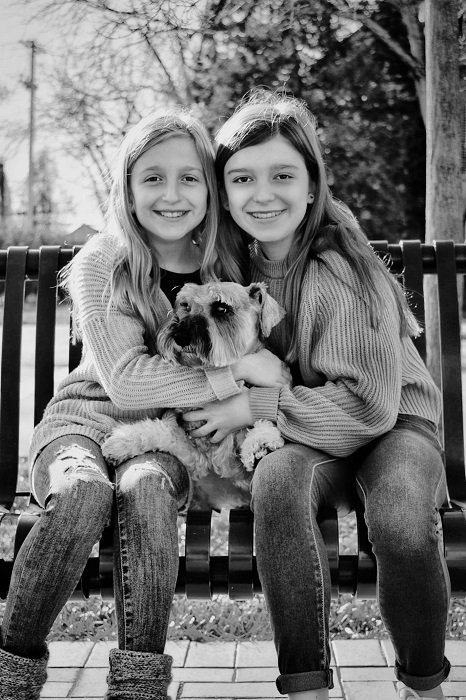 photo ideas for siblings: sisters sitting on a bench with their dog