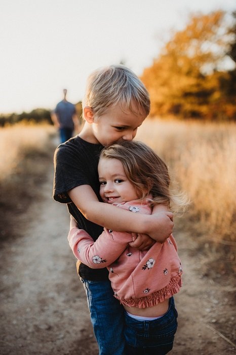 photo ideas for siblings: siblings hugging with a dirt path in the background