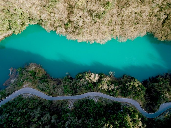 Tips for repetition in photography: View of a road and a river from above that share the same pattern cutting through a landscape