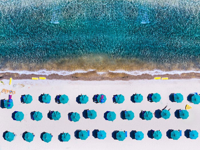 Repetition in photography: Aerial photograph of repeating umbrellas on a beach and ocean elements