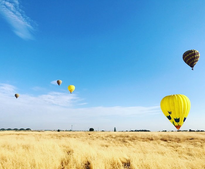 在摄影的节奏：飞行在一个麦田的热空气气球在大蓝天前面