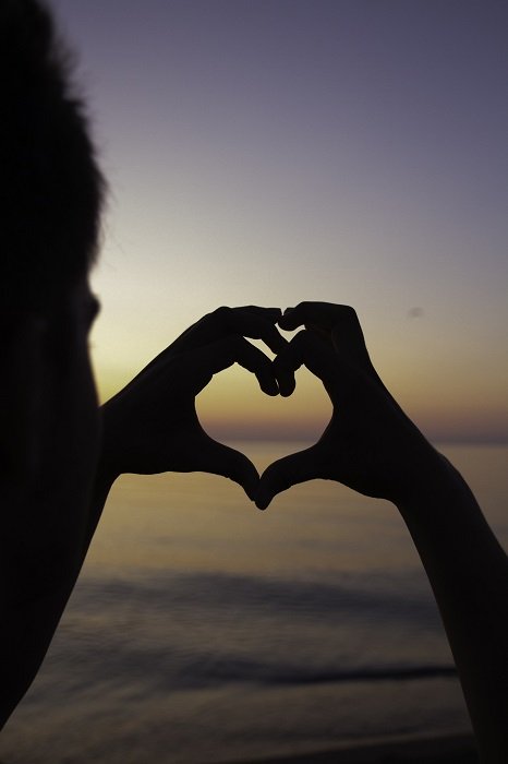 shape in photography: negative space in the shape of a heart created by hands which are in low light against the horizon