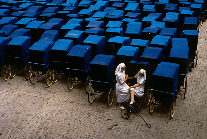 break the pattern in photography: an image of two nurses sitting amongst many blue rickshaws from Steve McCurry