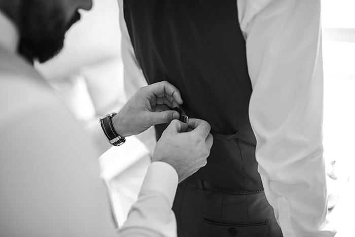 groomsmen getting ready: a black and white photo of a groomsman adjusting a waistcoat