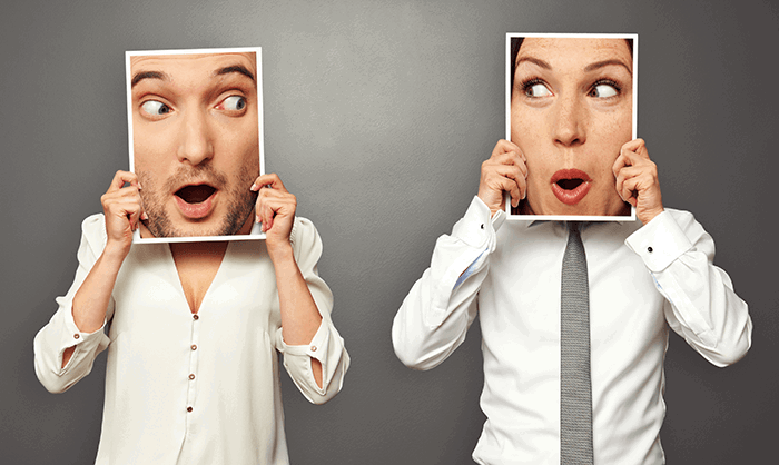 swapping faces: A man and woman holding up printed image of each other's faces illustrating face swap app possibilities