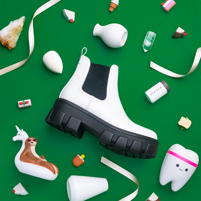 A messy flat lay product photography image with a large boot in the middle of random objects
