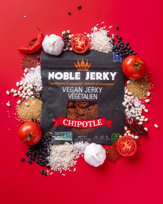 A flat lay product photography image of a bag of vegan chipotle jerky with fresh ingredients around it using soft light