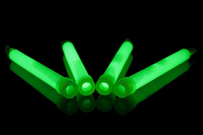 four neon green glow sticks in a completely dark setting