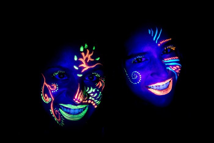 black light photography ideas: two people with ultraviolet paint on their faces shot in a darkroom