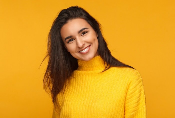 color blocking photoshoot tips: a portrait of a woman wearing an orange sweater in front of an orange backdrop