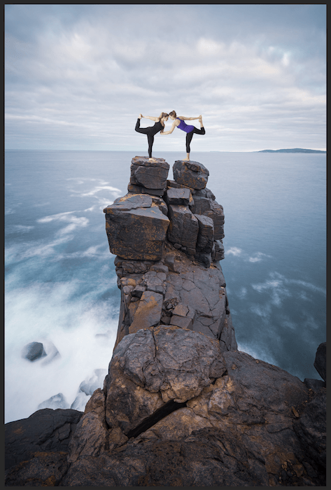 Cut out image of women in yoga pose place on top of a cliff in Photoshop for composite photography
