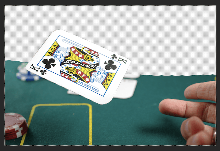motion blur in photoshop: A photo of a playing card being thrown on a table with half its background erased in Photoshop