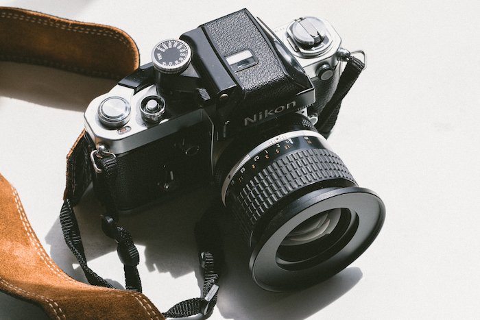 a vintage Nikon film camera with a brown leather strap with Lens Abbreviations