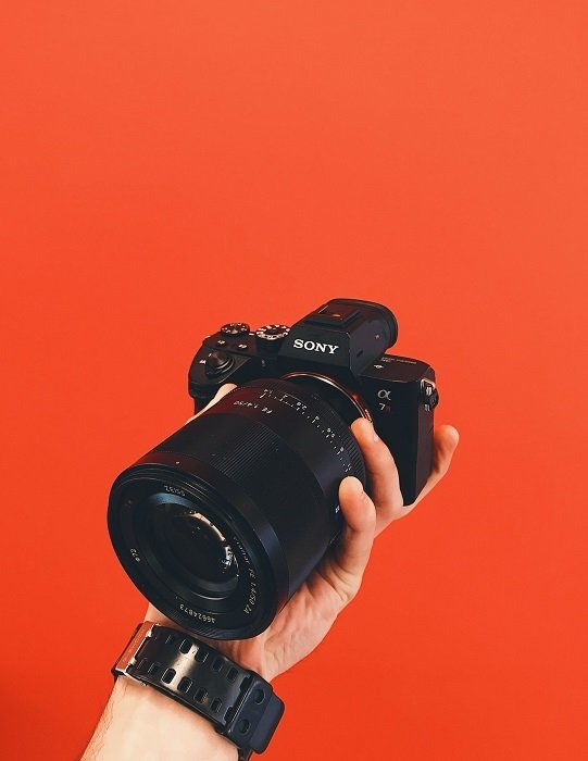 a Sony a7 held in the photographers hand with an all red background