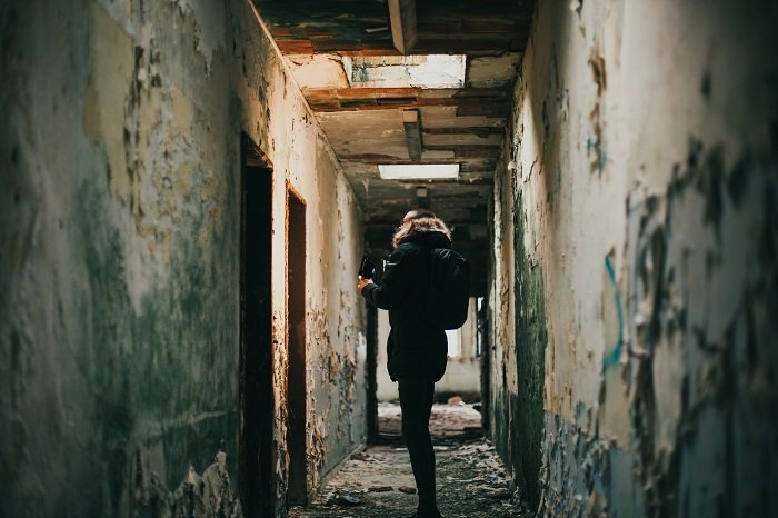 urban exploration: a photographer walking through a dark hallway in an abandoned building