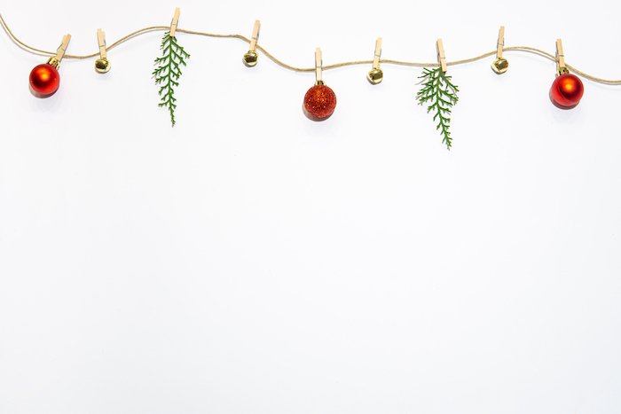 Minimalist Christmas flat lay of sting decoration with red ornaments bells and tiny pine branches
