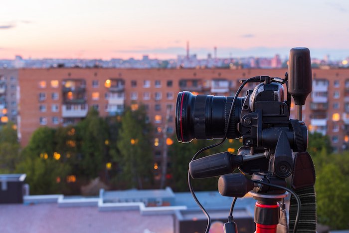 DSLR camera on a tripod with an evening cityscape in the background