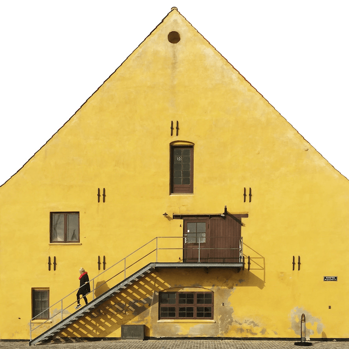 city photography: A person walking down a staircase in front of a large yellow building
