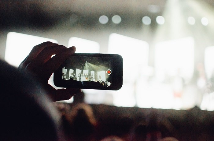 a smartphone photographer snaps a photo of a live concert