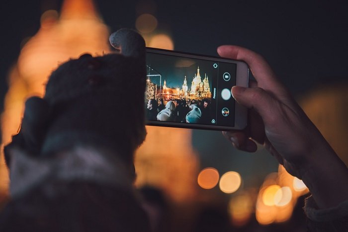 a smartphone photographer captures a night scene of illuminated buildings