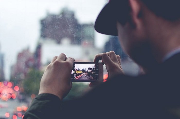 a photographer uses his smartphone to take a photo of a cityscape