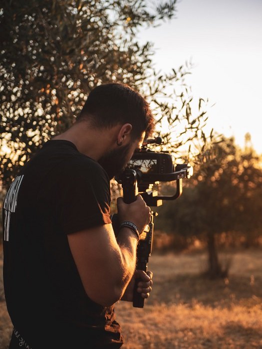 a videographer uses a stabilizer to shoot video of a sunset