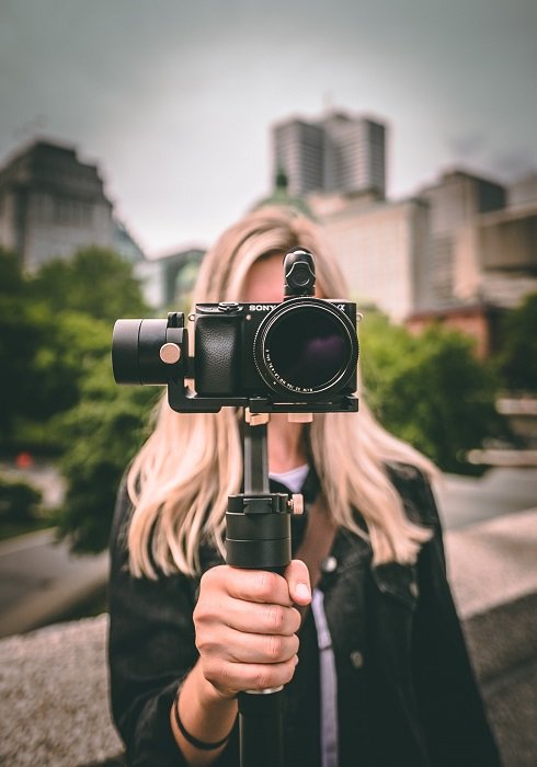 a head on shot of a woman holding a camera mounted to a stabilizer