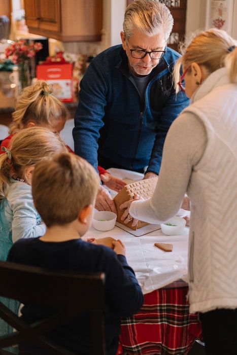 A family putting together a gingerbread house for Christmas card photo ideas